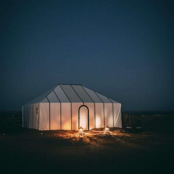 A luxury desert camp in the Sahara Desert, featuring elegant tents set against a star-filled night sky, offering a unique and lavish desert experience.
