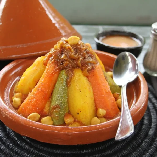 A traditional Moroccan tagine with lamb, prunes, and couscous, served on a vibrant platter